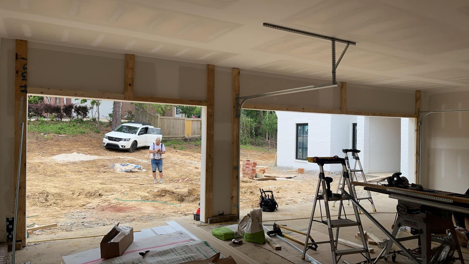 A garage under construction with a car parked in the backyard.