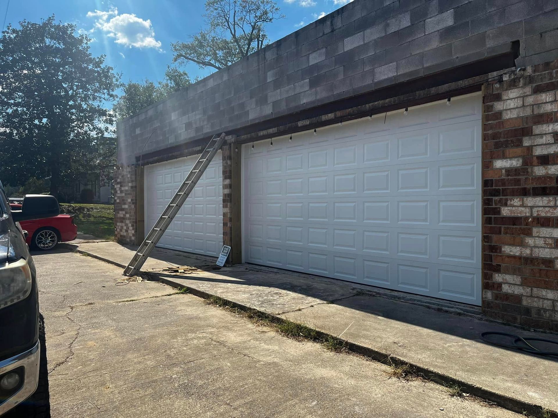 A white garage door is being installed on a brick building.