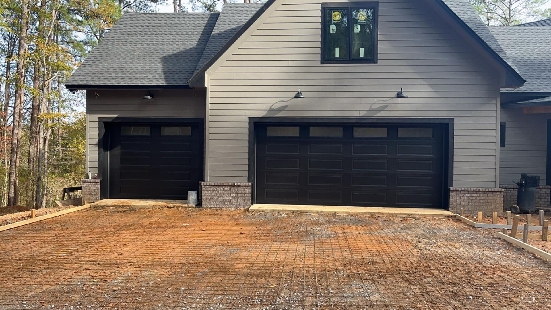 A house with two garage doors and a driveway in front of it.