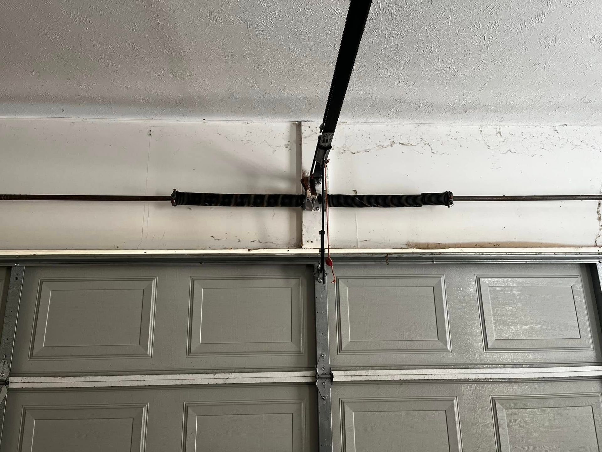 A close up of a garage door with a spring hanging from the ceiling.
