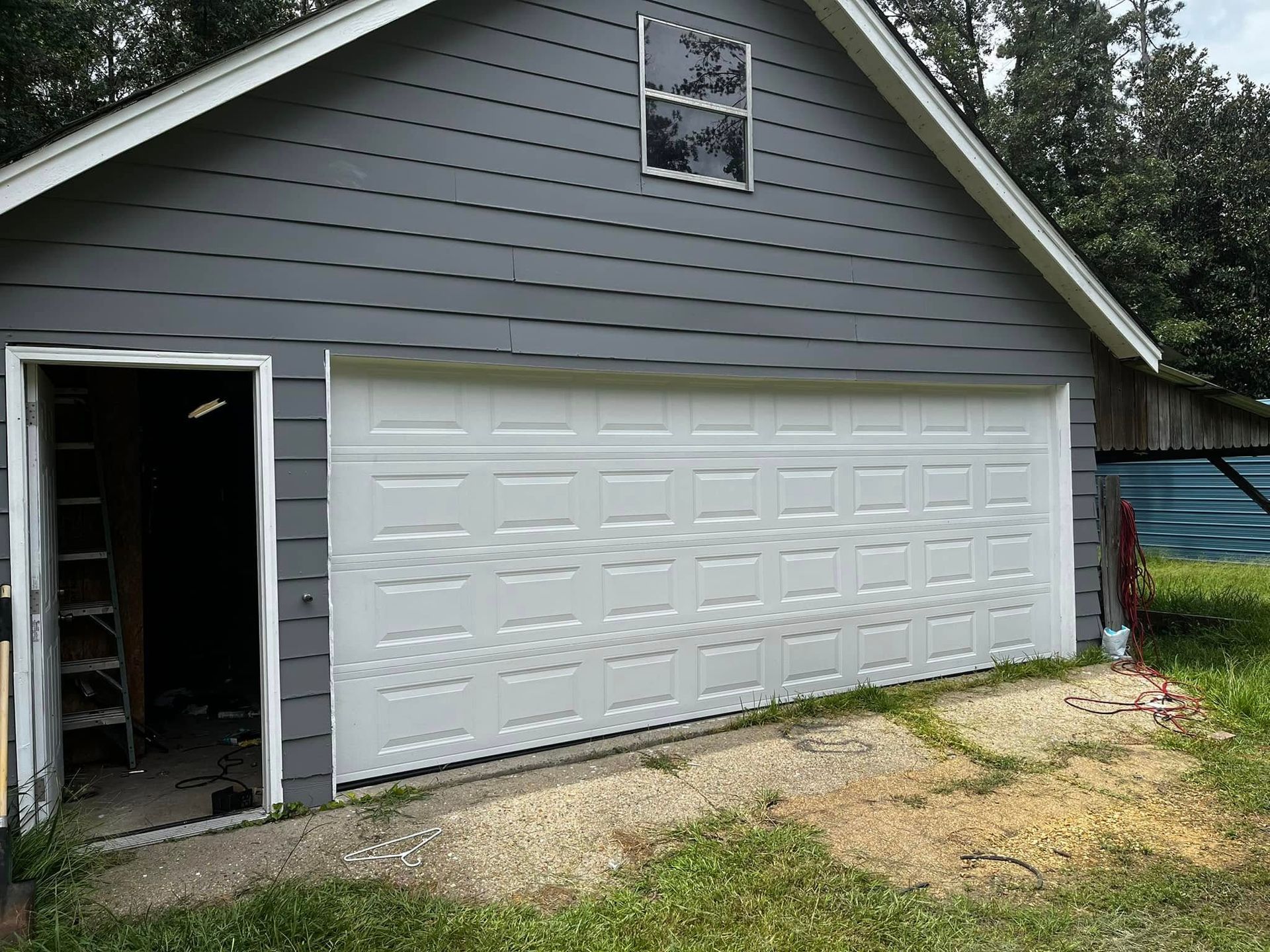 A garage with a white garage door and a ladder in front of it.