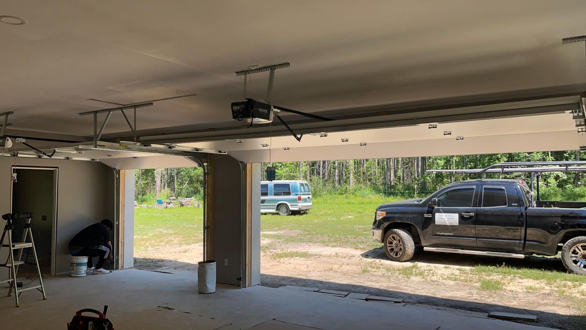 A black truck is parked in a garage with the door open.