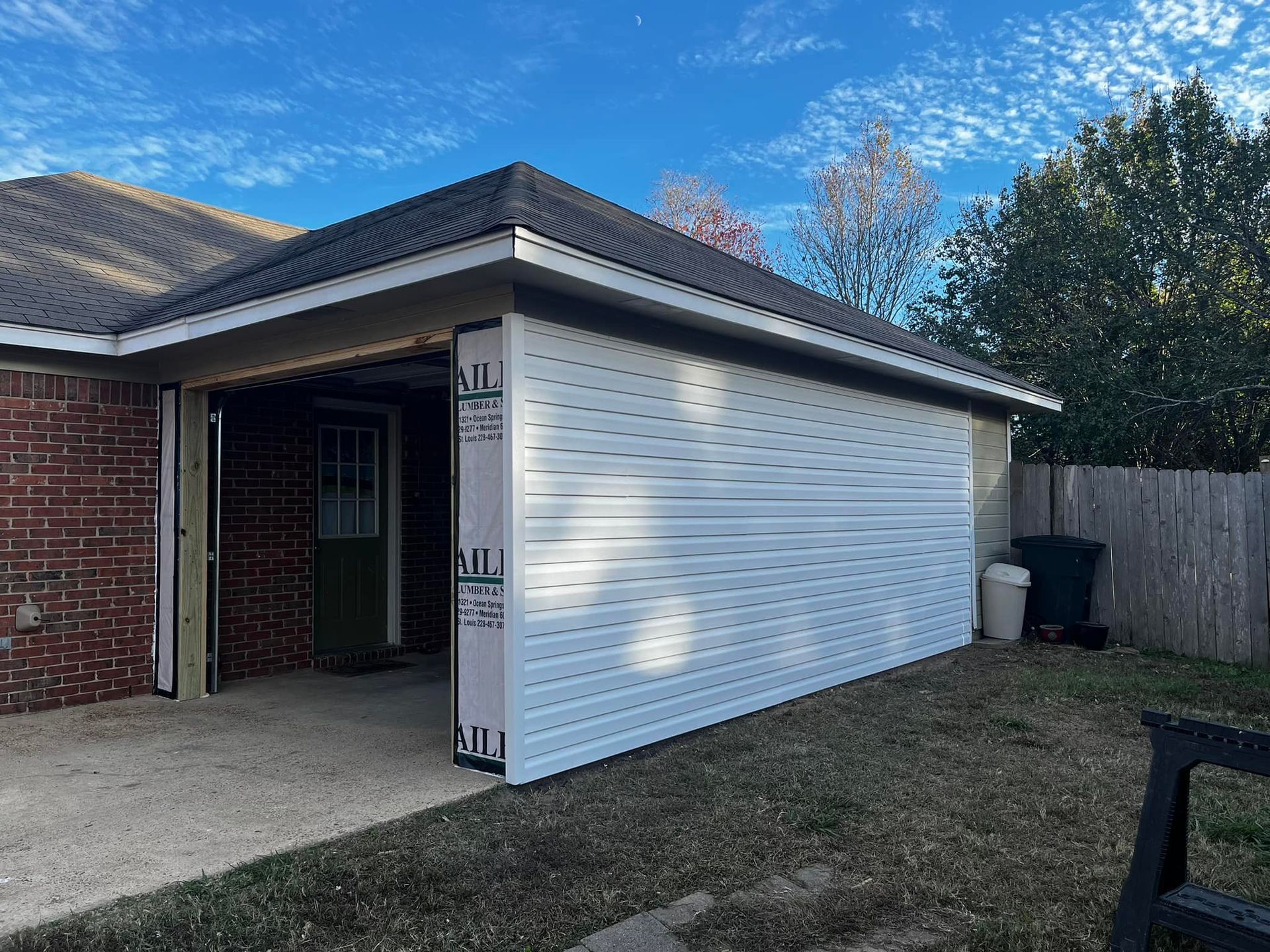 A white garage door is being installed on the side of a brick house.