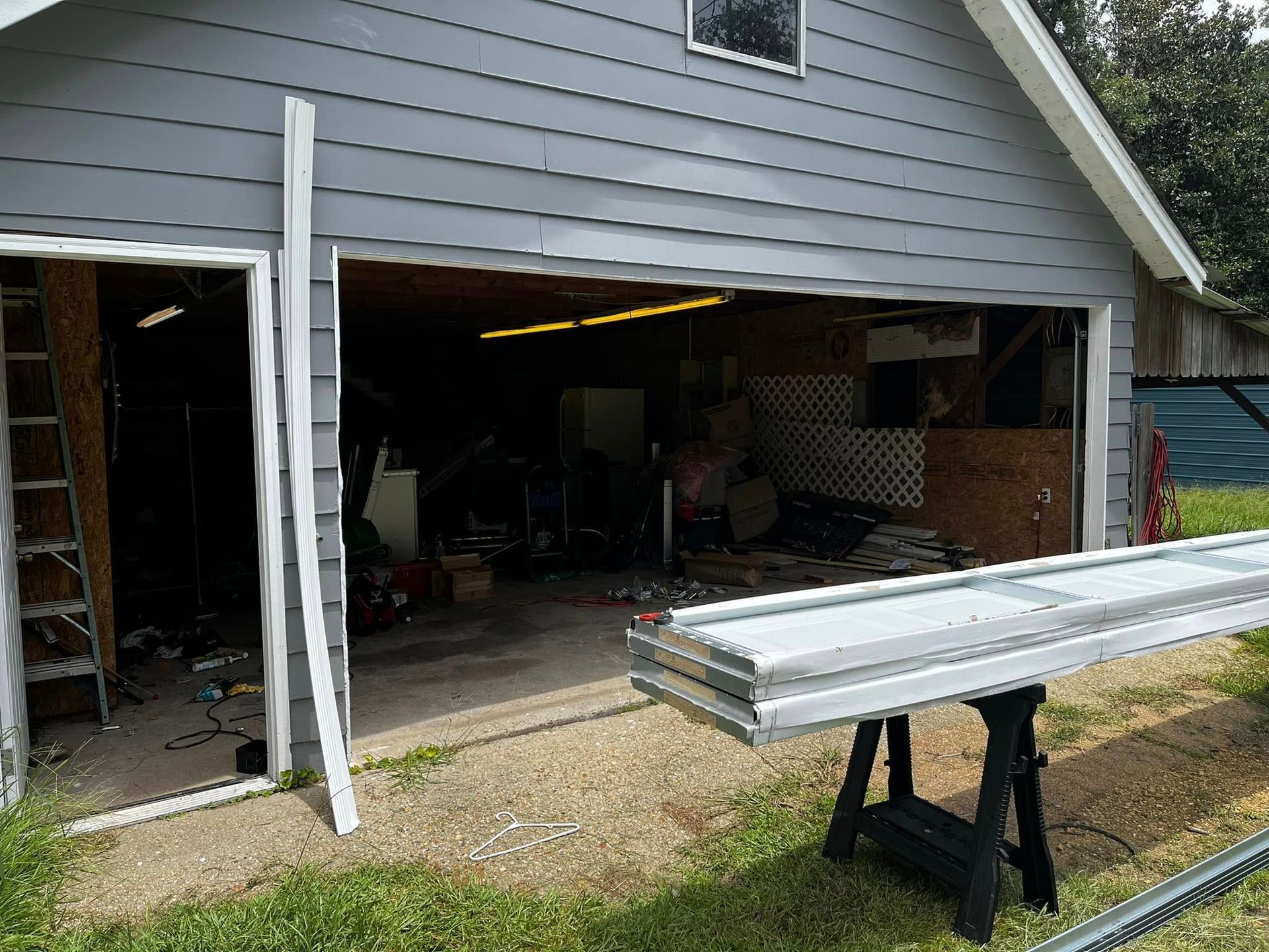 A garage door is open and a piece of wood is sitting on a table in front of it.