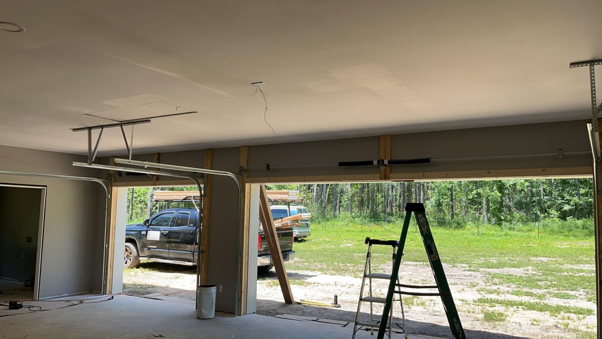 A garage under construction with a ladder and a car parked in it.