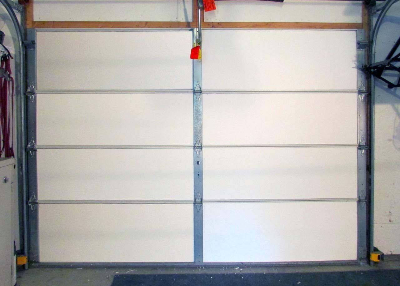 A white garage door is open in a garage.