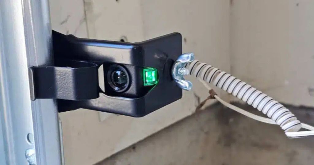 A close up of a garage door with a green light on it.