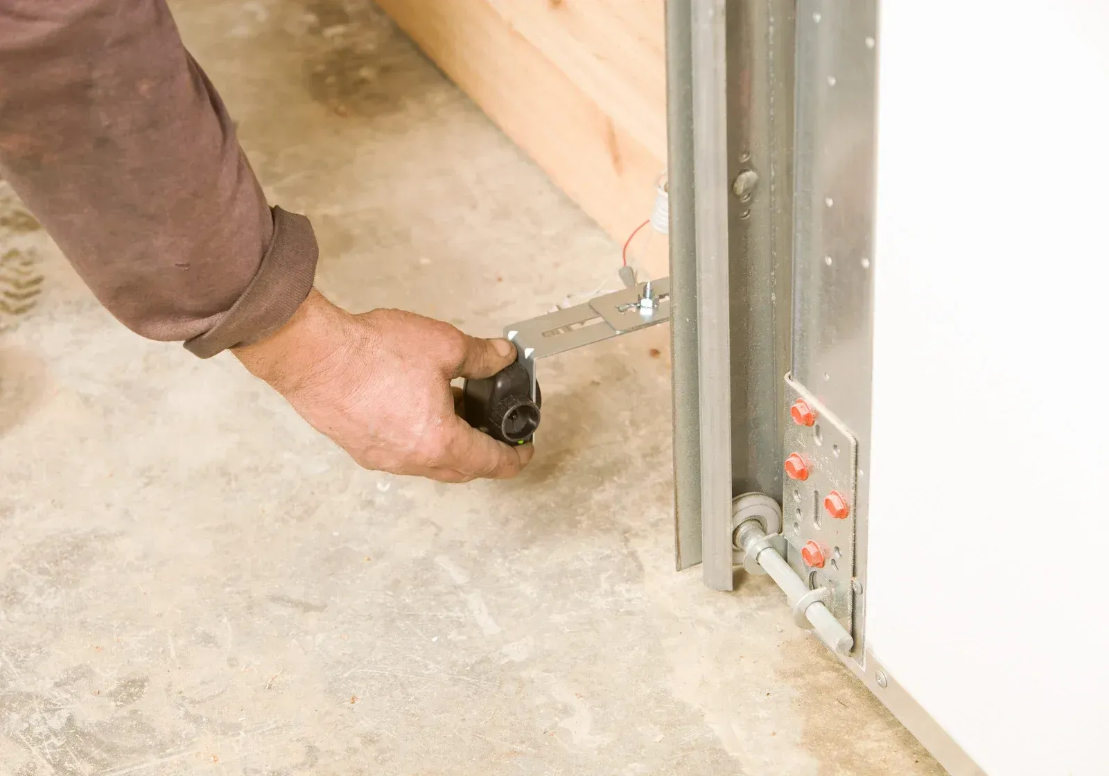 A man is fixing a garage door with a wrench.
