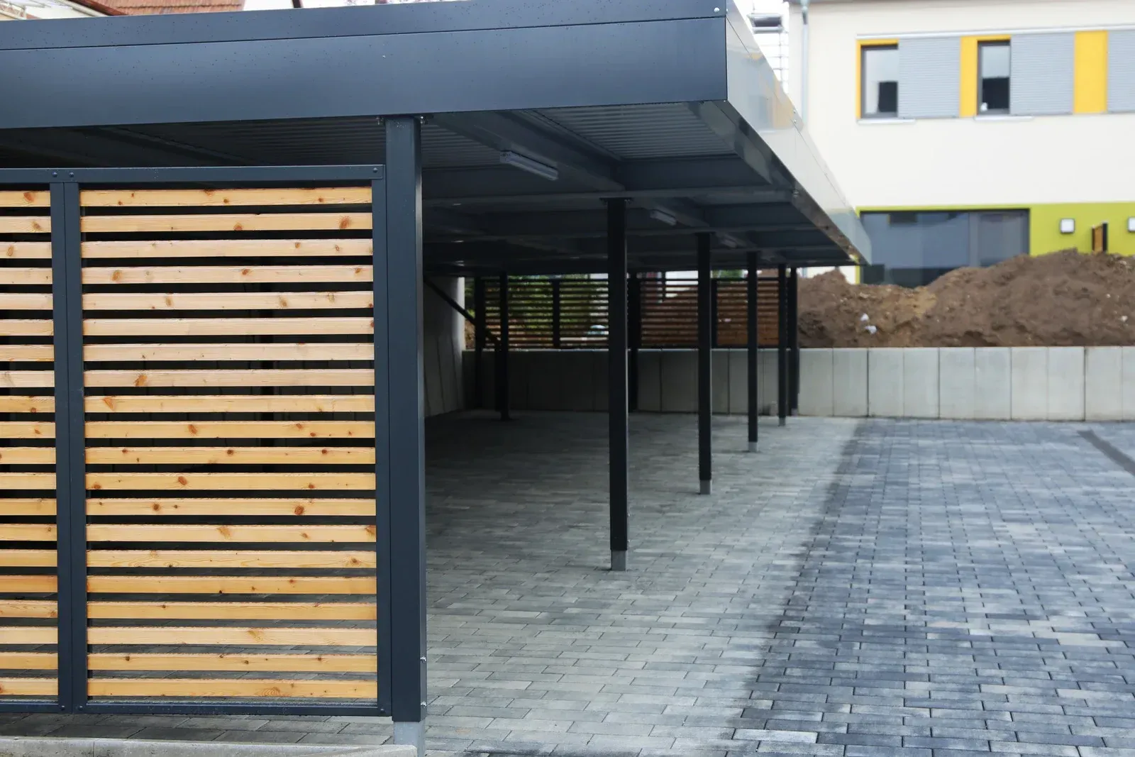 A carport with a wooden fence in front of a building.