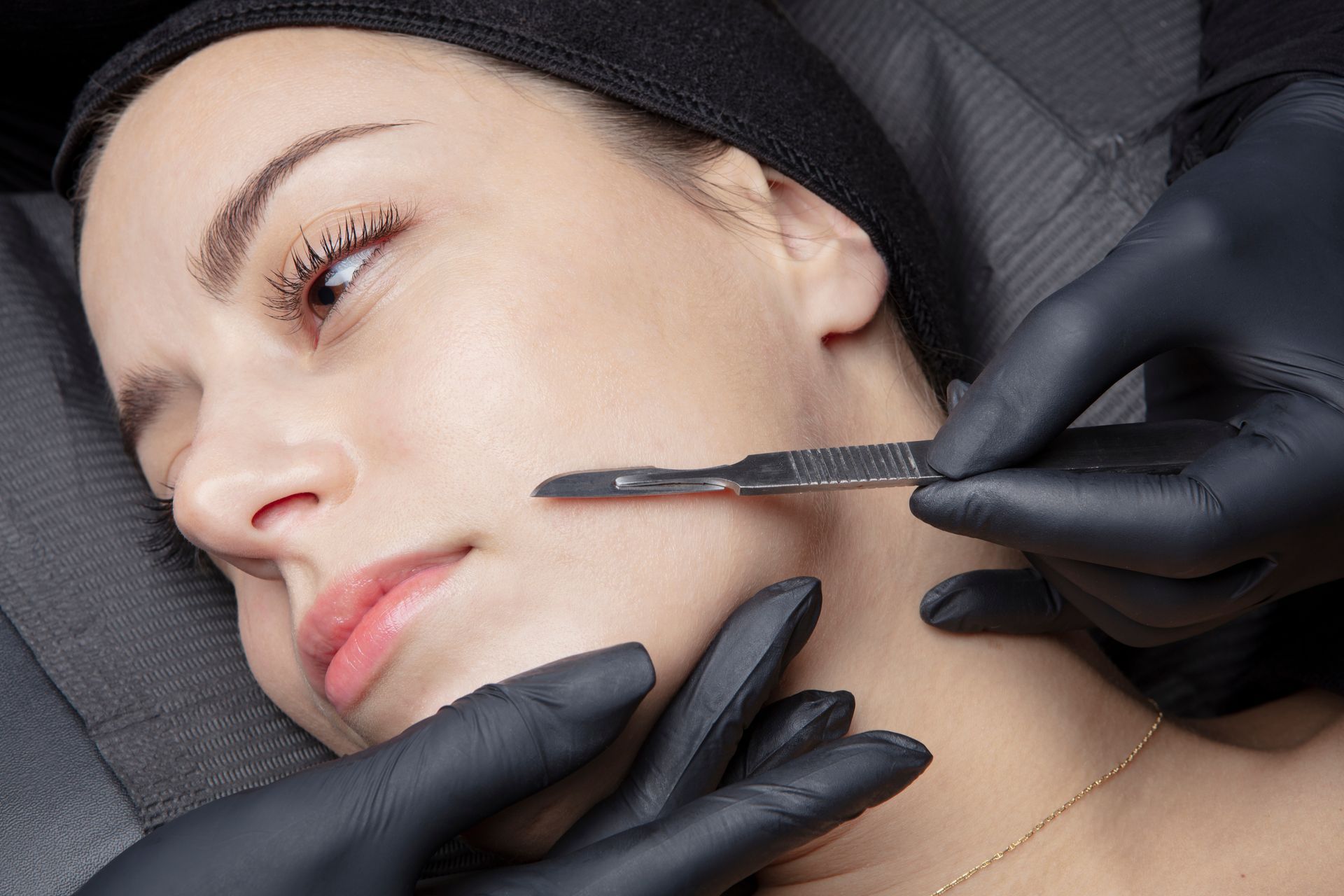 Professional dermaplaning treatment removing facial hair with sterile blade on client skin.