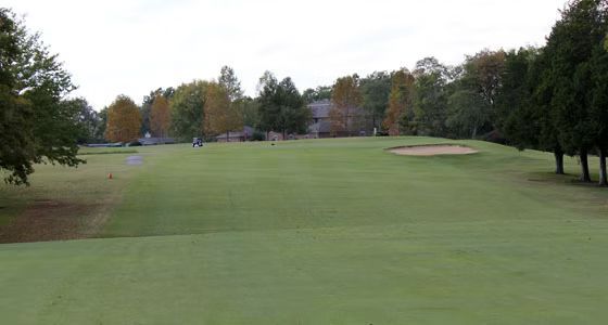 A golf course with a lot of green grass and trees in the background.