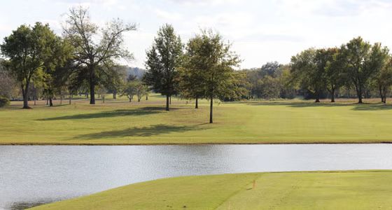 A golf course with trees and a pond in the middle