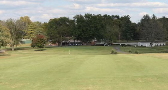 A golf course with a lot of green grass and trees in the background.