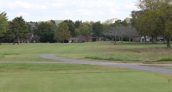 A golf course with a path going through it and trees in the background.