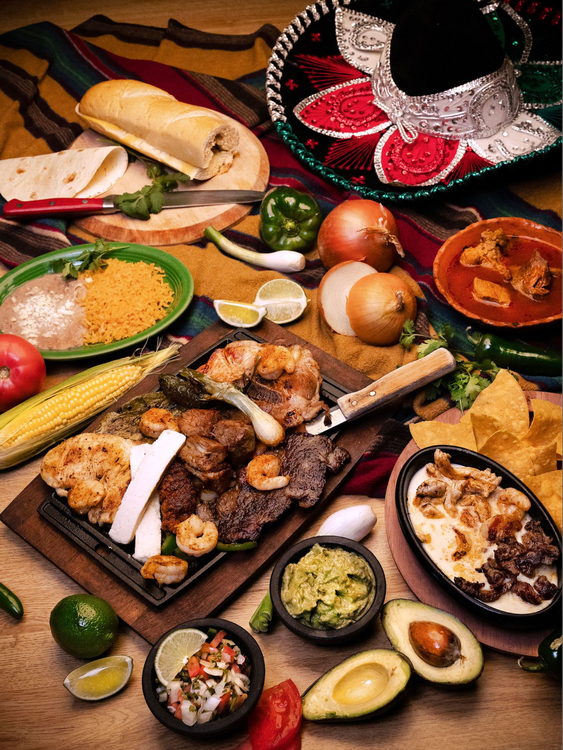 Mexican food spread: fajitas, tortillas, beans, rice, chips, guacamole, salsa, sombrero.