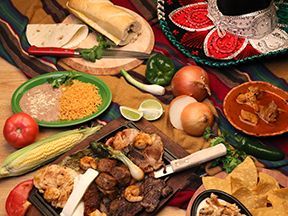 Mexican food spread, featuring tacos, beans, rice, meat, and vegetables.