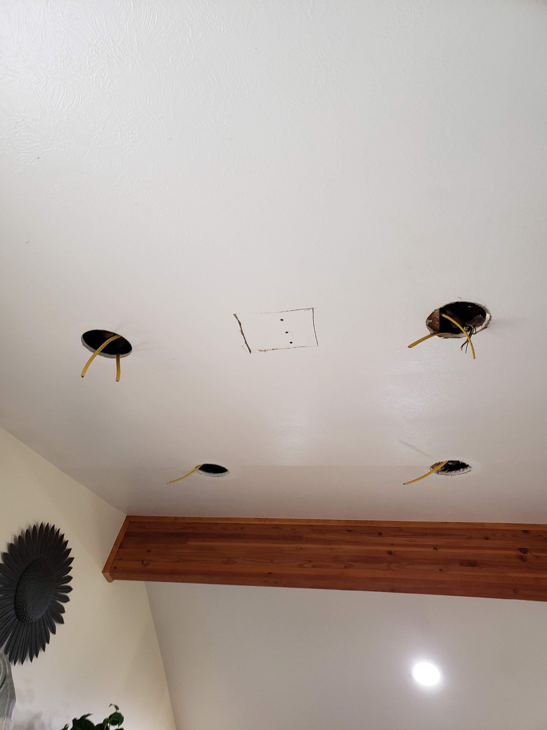 A white ceiling with holes in it and a wooden beamed ceiling.