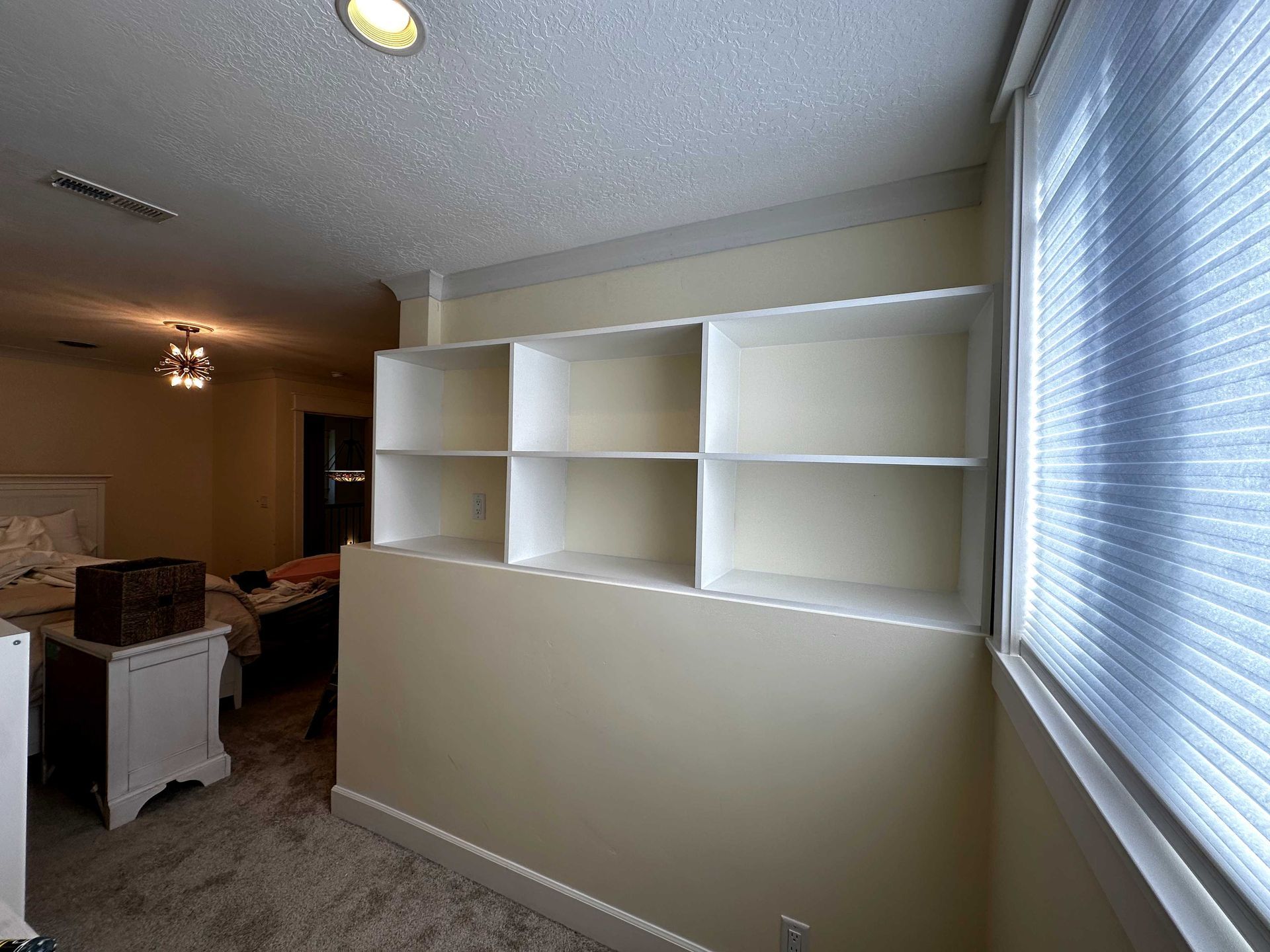 A room with a lot of shelves and a window.