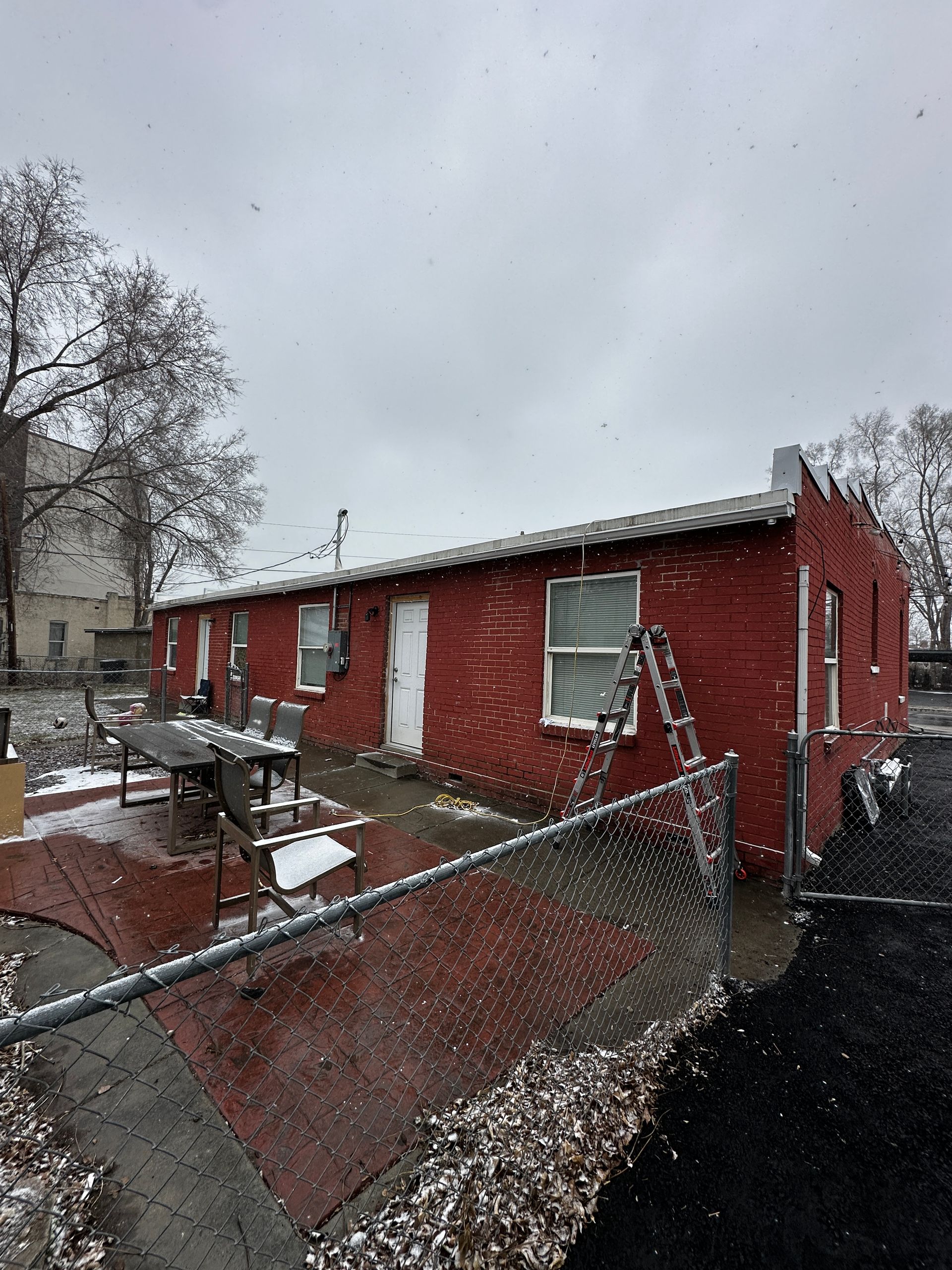 A red brick house with a chain link fence in front of it