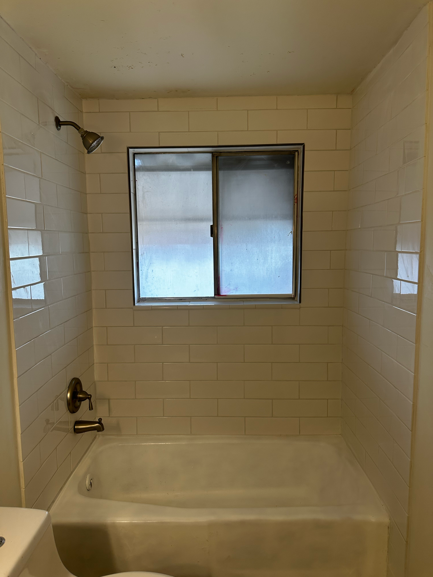 A bathroom with a tub , shower , sink and window.