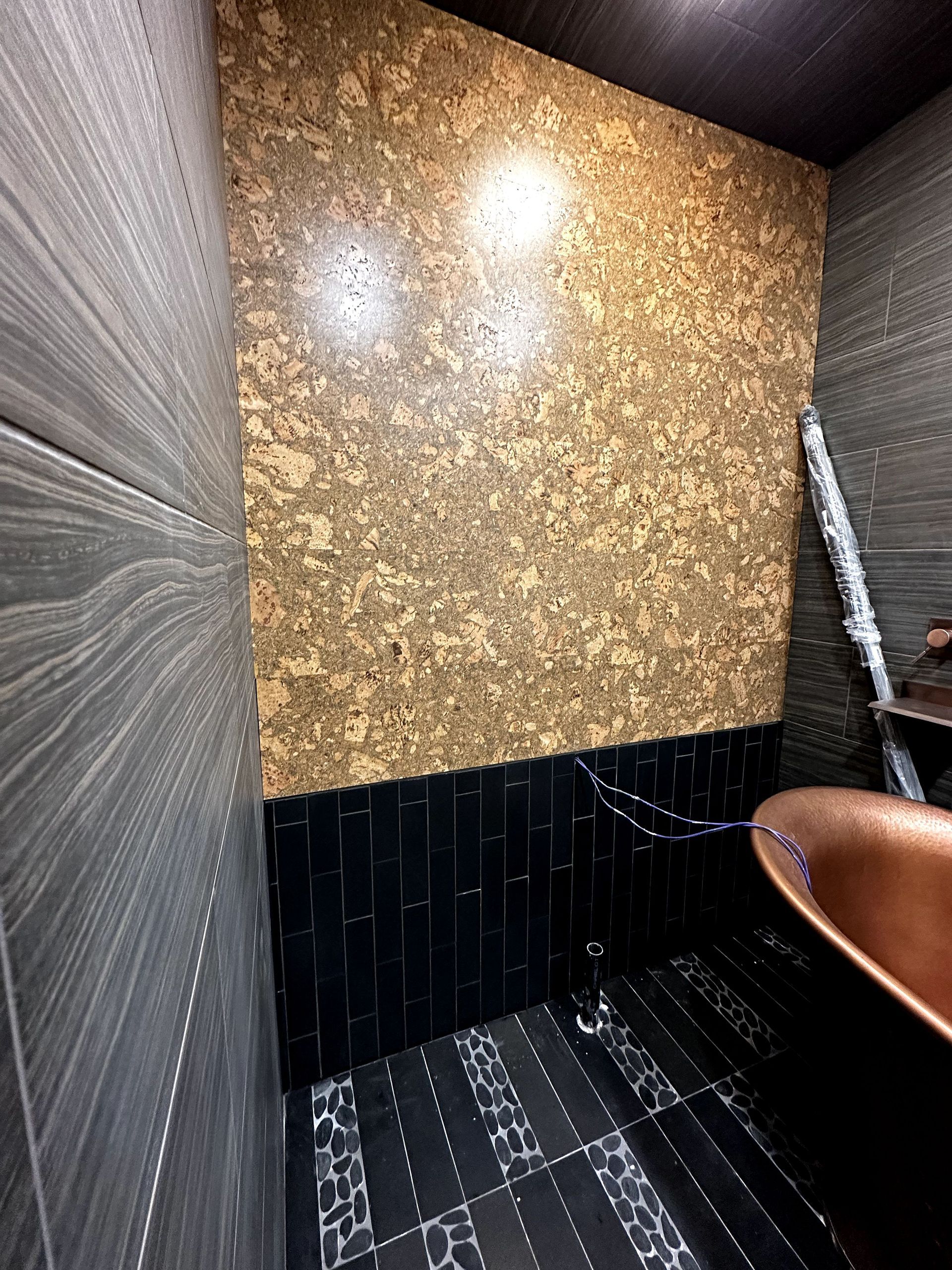 A bathroom with black tiles and a copper sink.