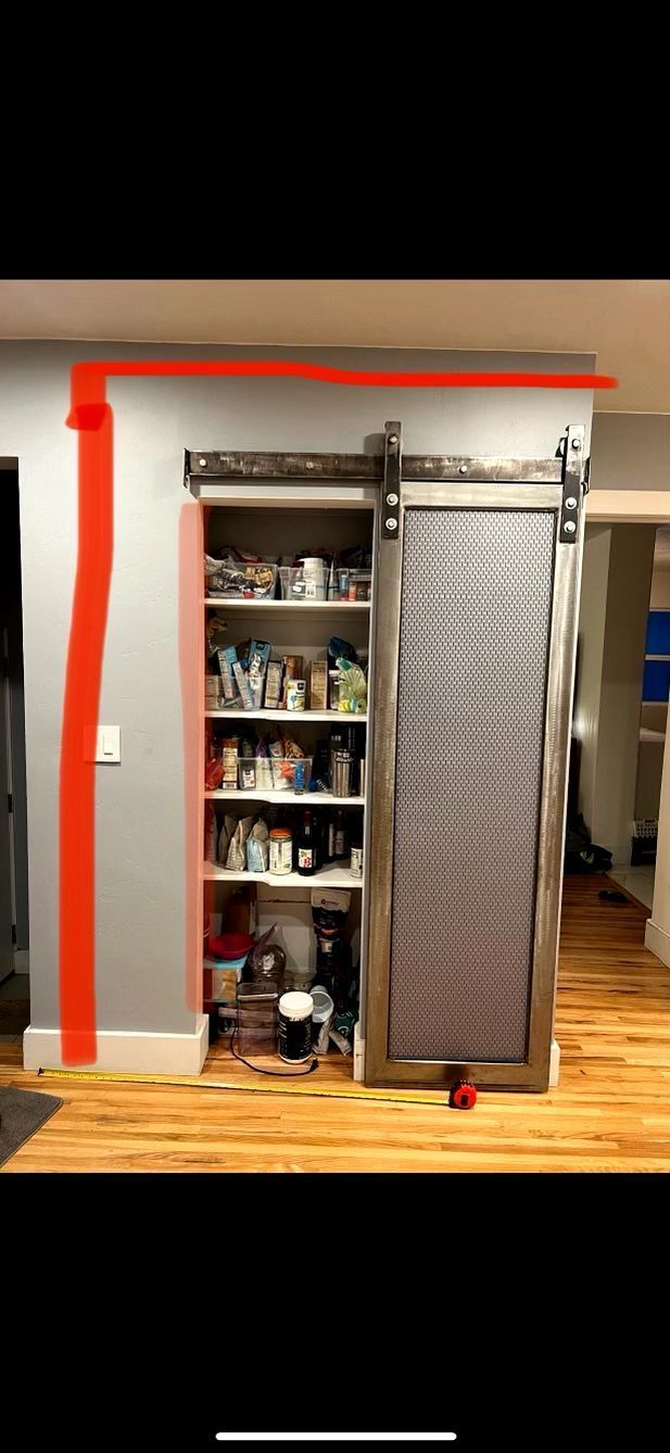 A pantry with a sliding barn door and a red line on the wall.