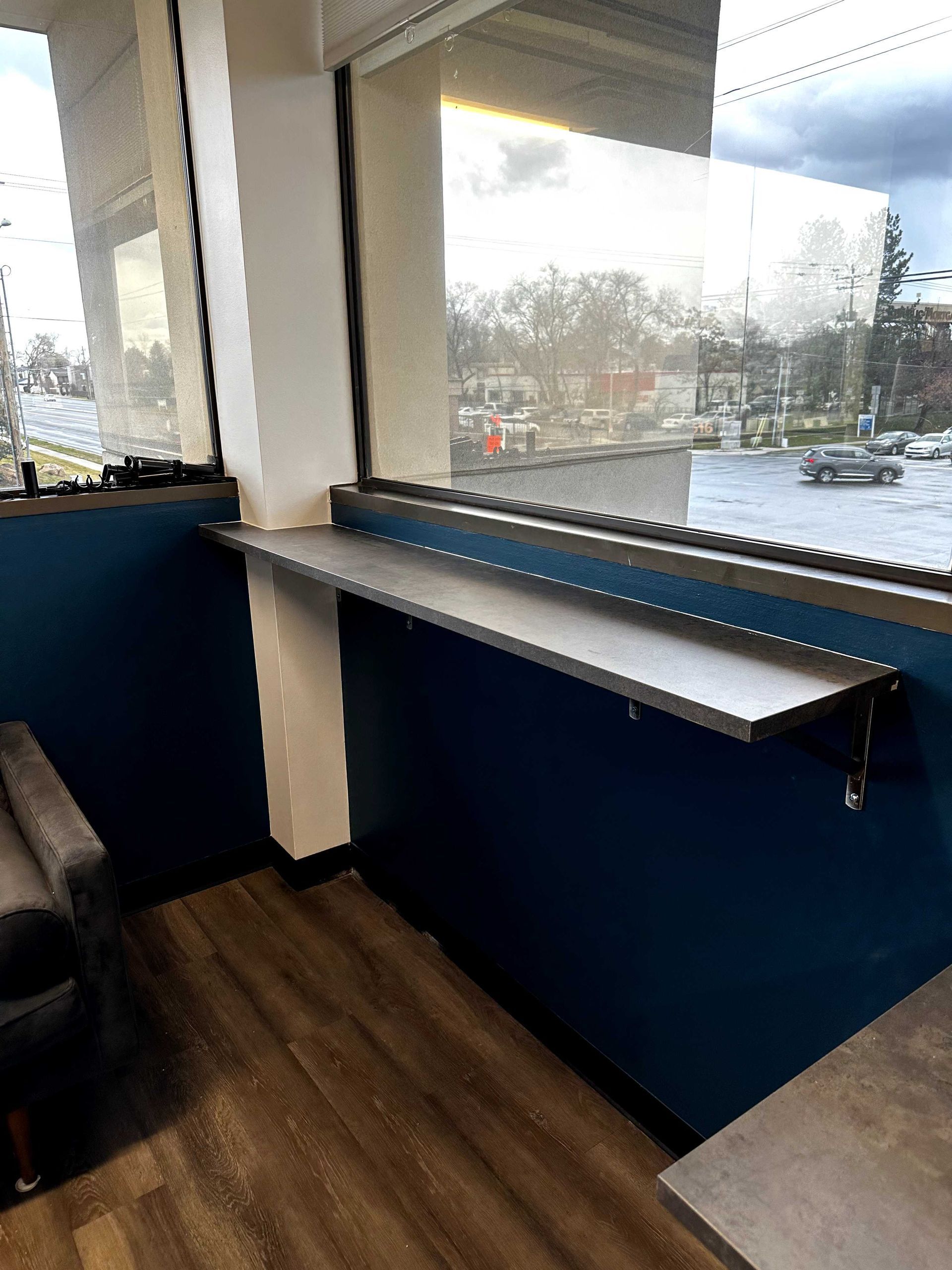 A room with a window and a shelf in front of it.