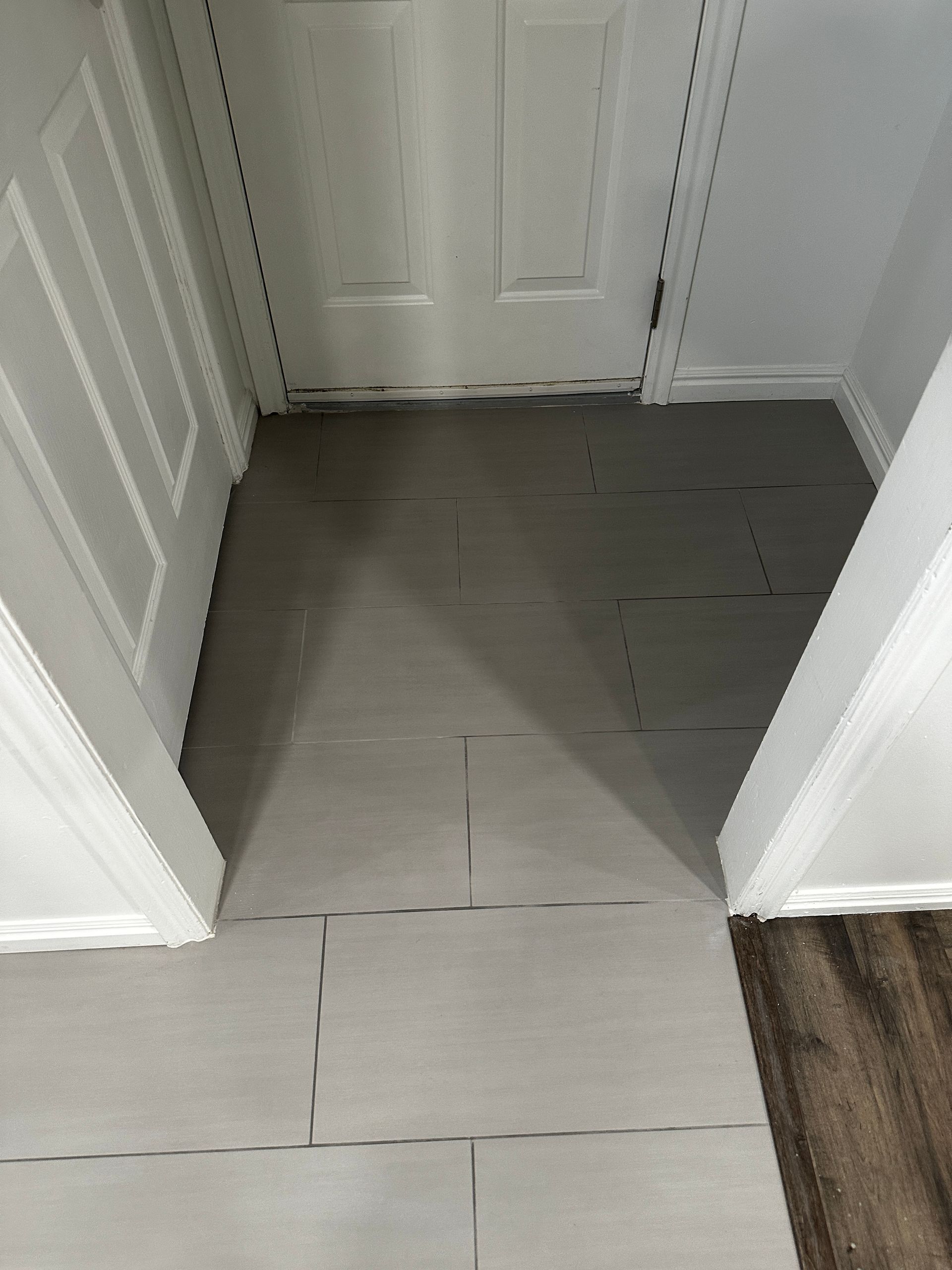 A hallway with a tiled floor and a white door.