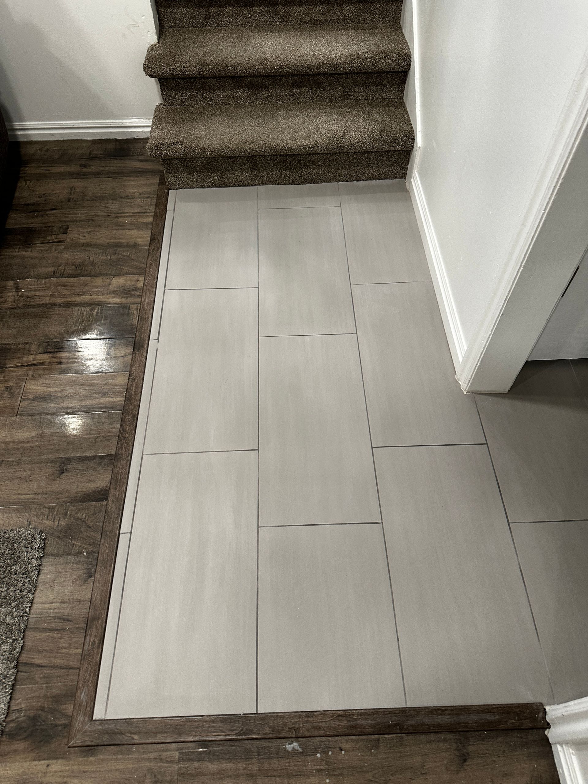 There is a staircase in the background and a tiled floor in the foreground.