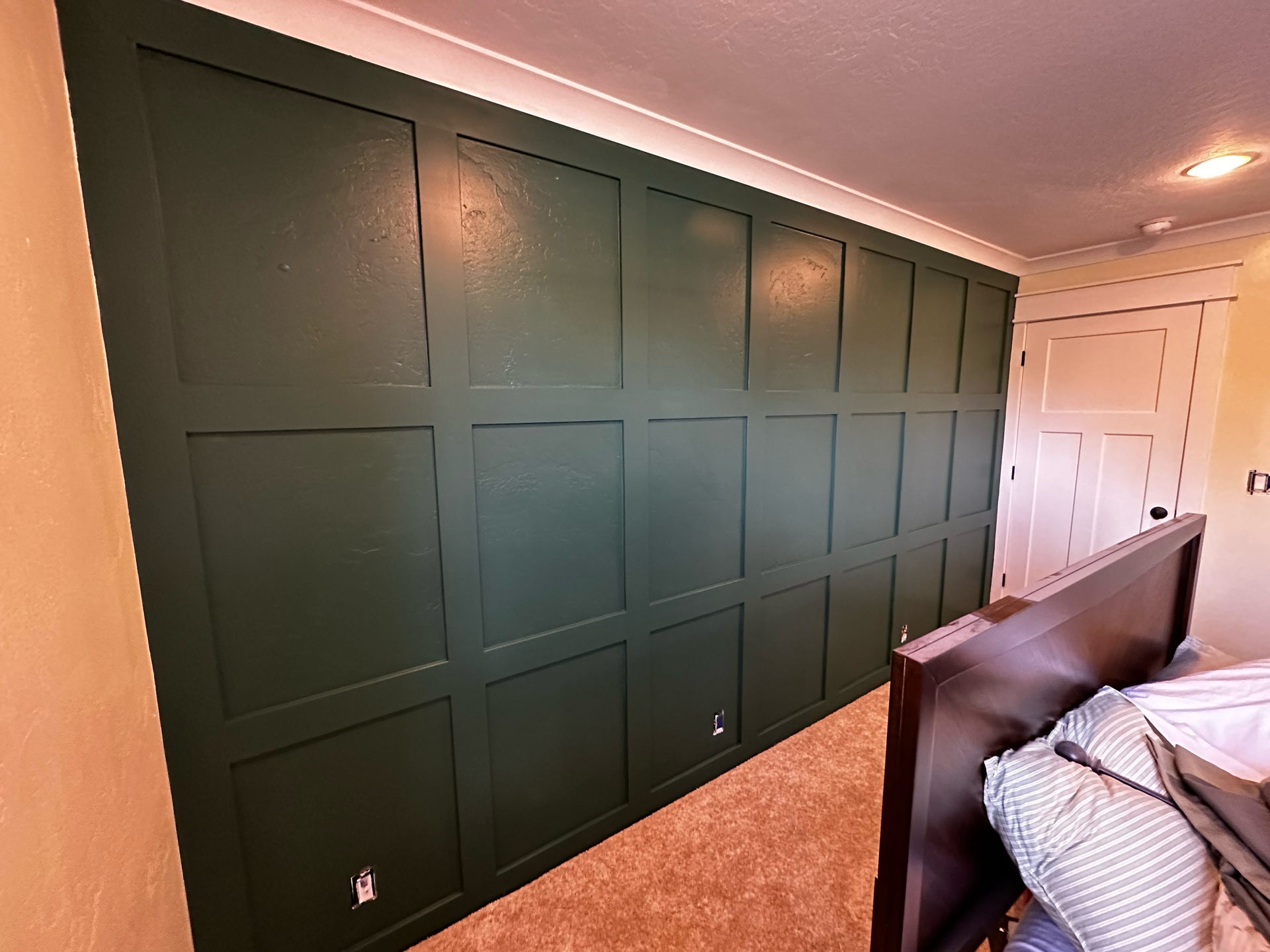 A bedroom with a large green wall and a bed.