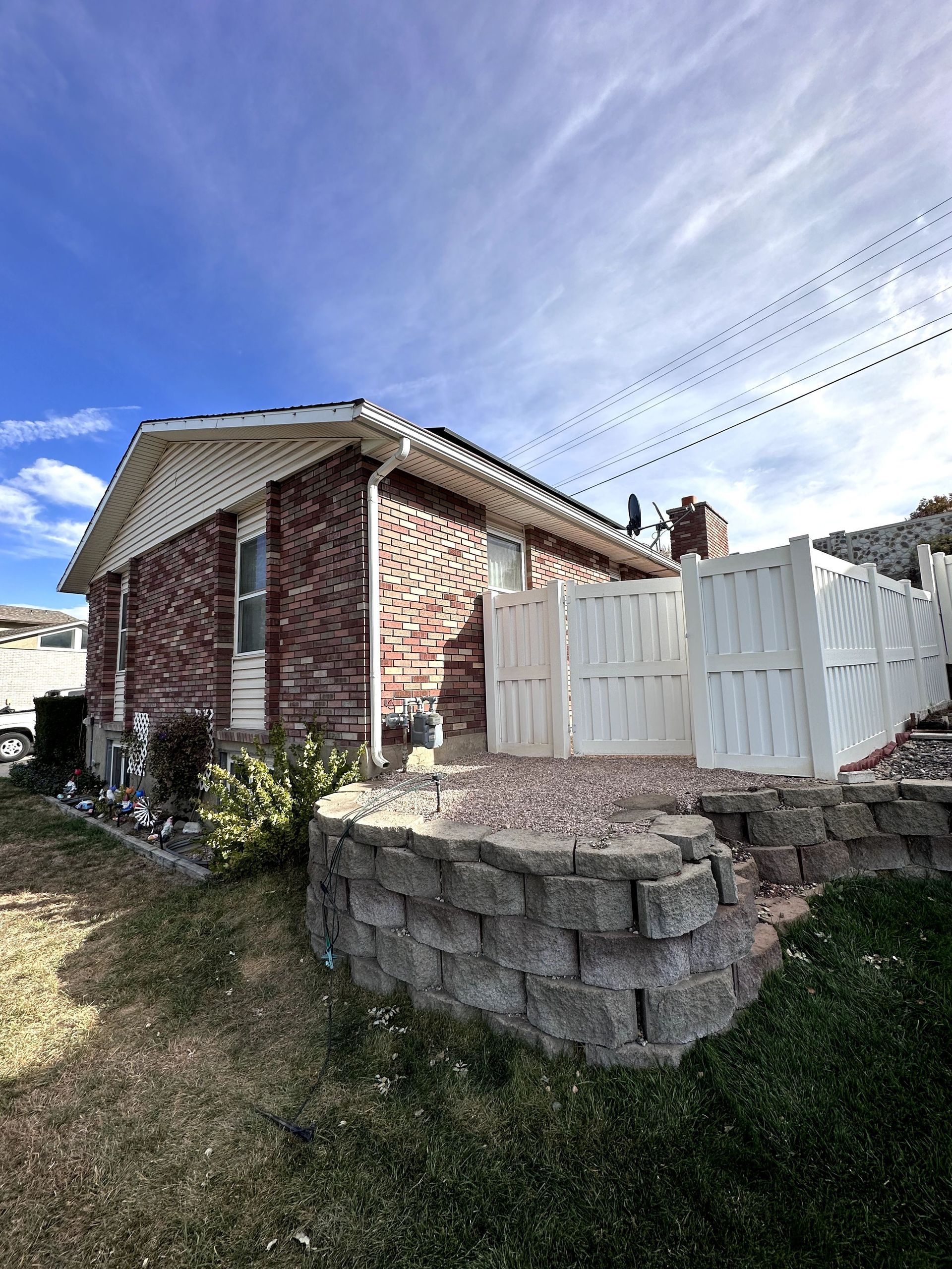 A brick house with a white fence and a stone wall in front of it.