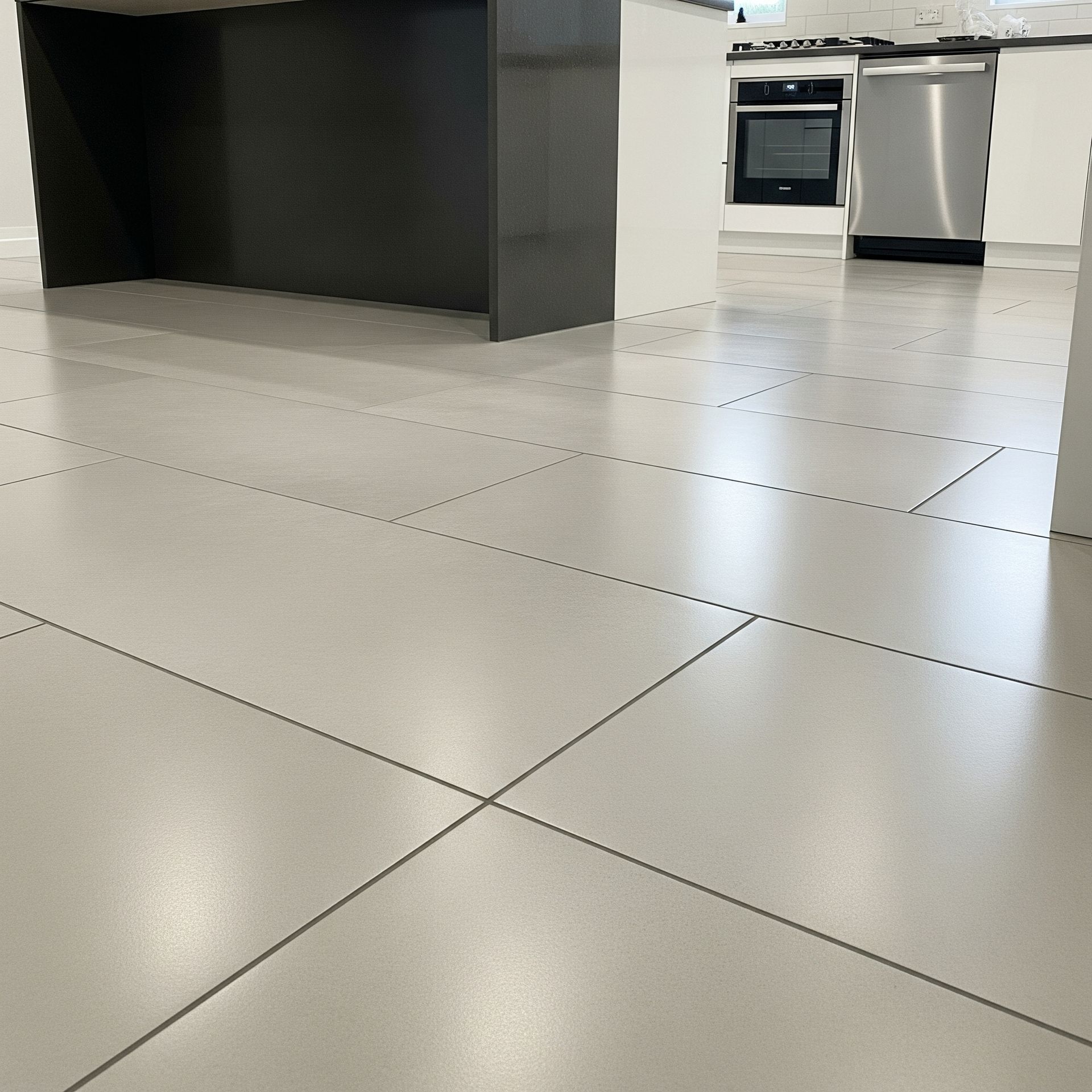 Gray tiled kitchen floor with a dark gray island and white cabinets and appliances.