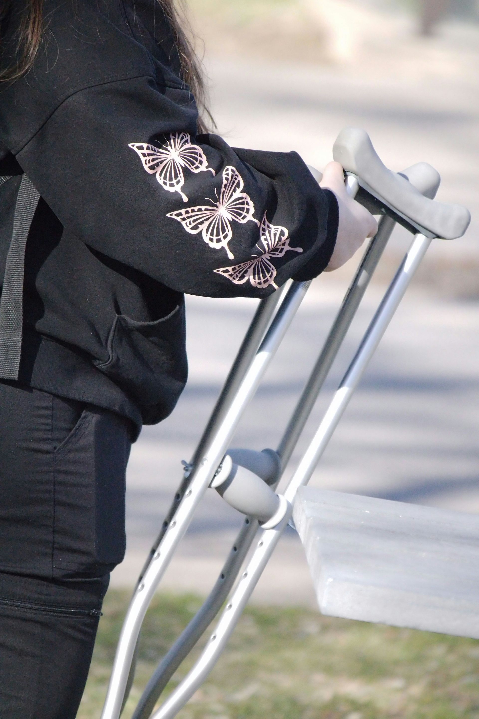 An elderly couple is walking on the beach with a walker.