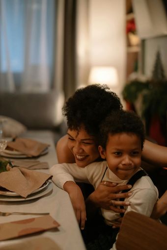 A woman is kneading dough with a baby in her arms.