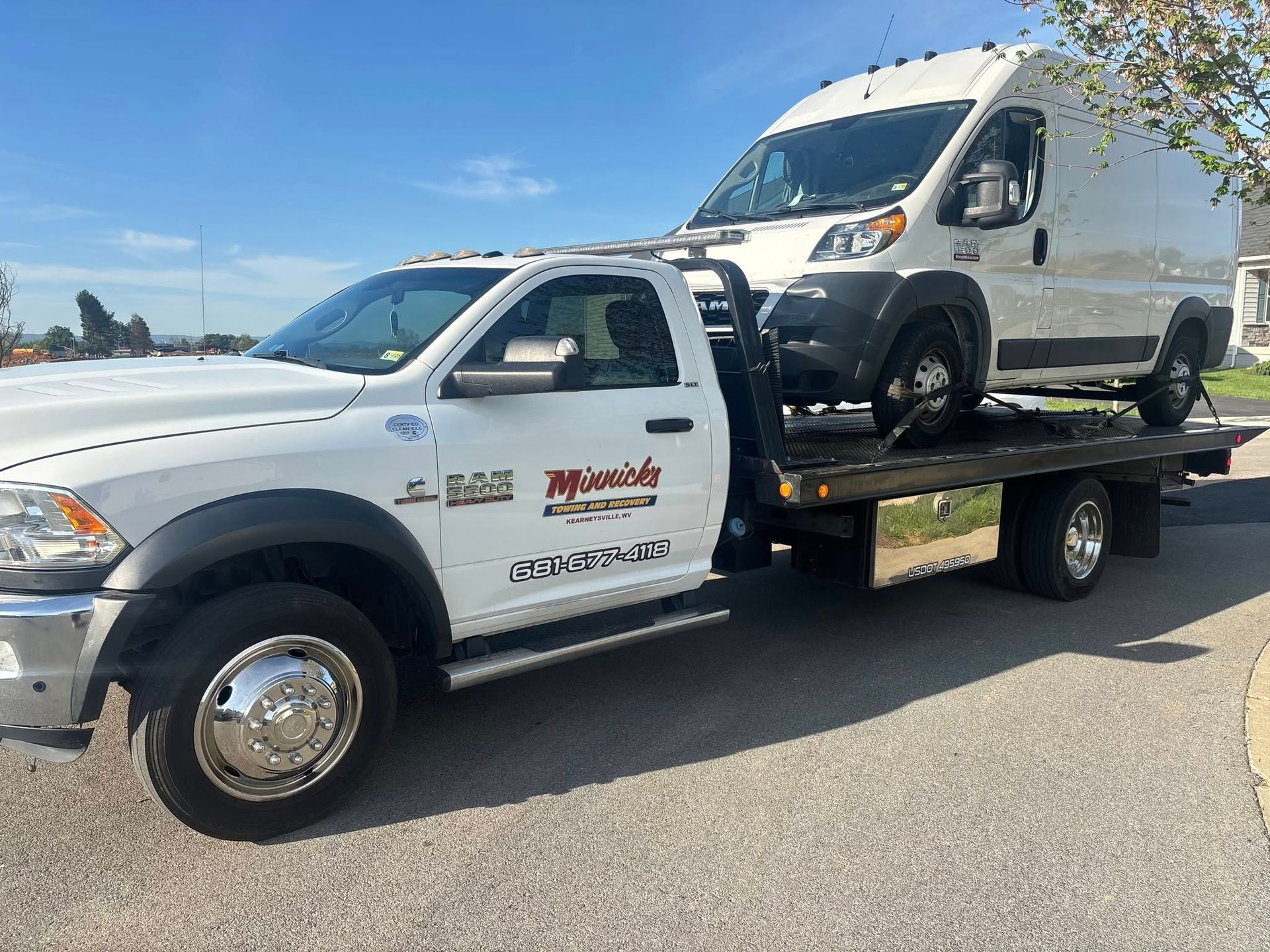 White tow truck hauling a white cargo van on a sunny day.