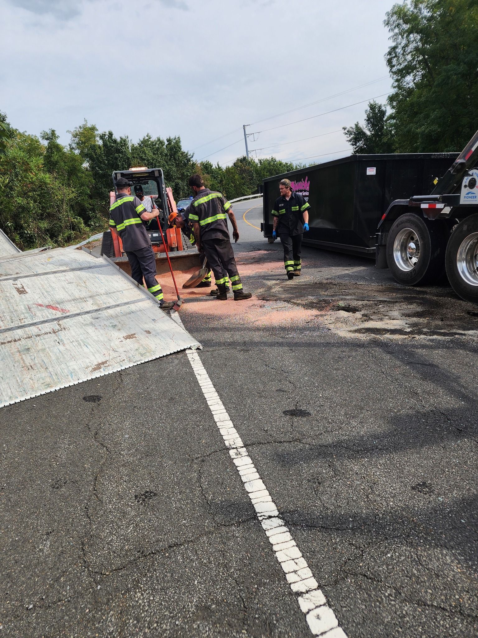 Firefighters working at the scene of a dump truck incident on a road.