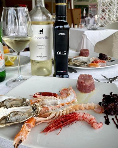 Piatto di frutti di mare con ostriche, gamberi e vino al tavolo di un ristorante.