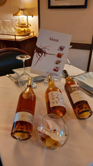Apparecchiatura del tavolo in un ristorante con tre bottiglie di vino, menù, bicchieri e una ciotola di caramelle.