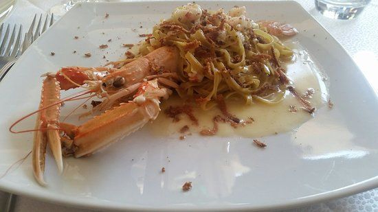 Piatto di pasta con uno scampo grande su un piatto bianco.