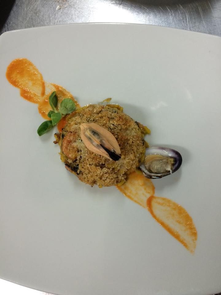 Piatto di frutti di mare, impanato con cozze, vongole e salsa all'arancia, disposto su un piatto bianco.