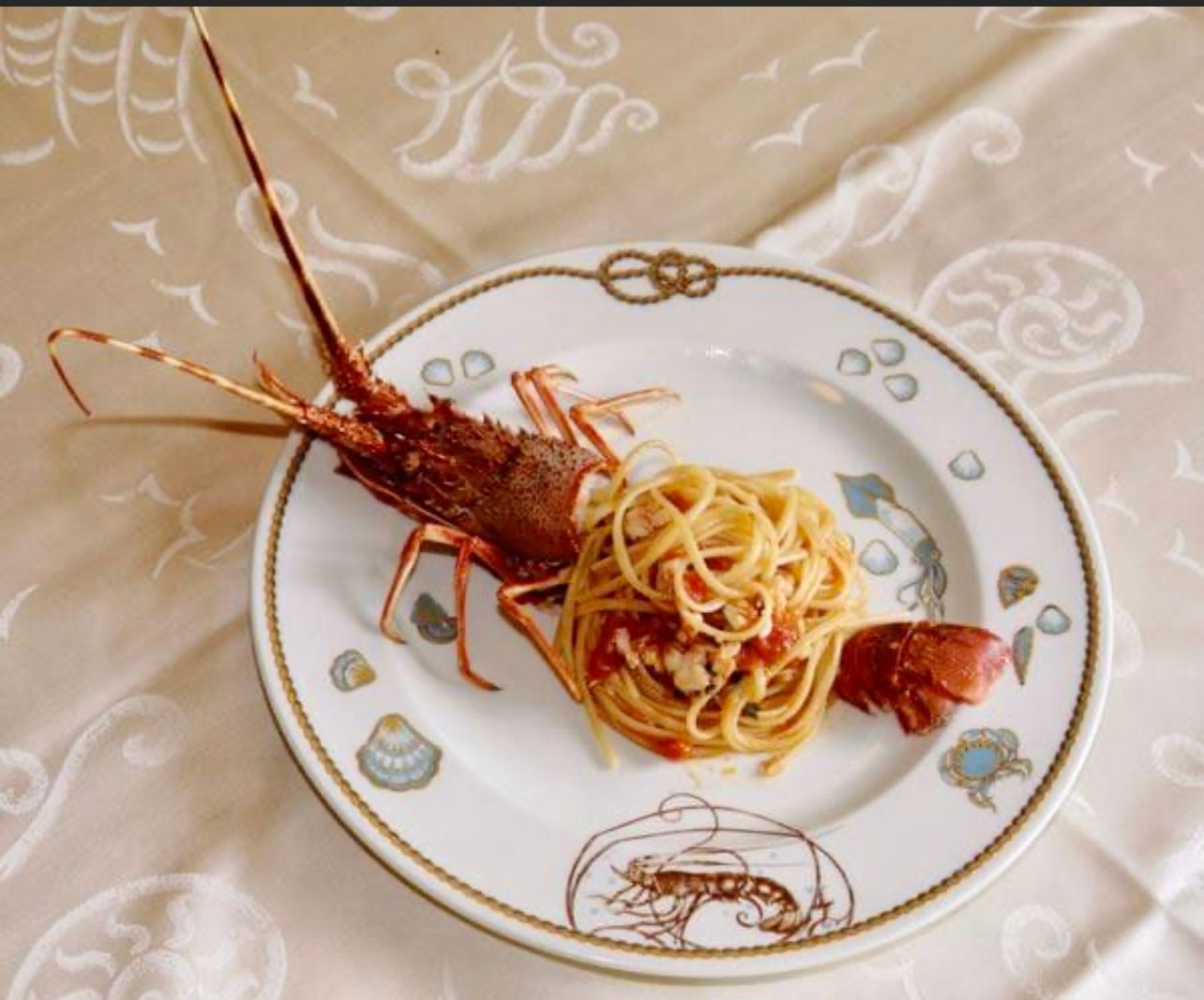 Piatto di aragosta e spaghetti su un piatto decorativo a tema nautico.