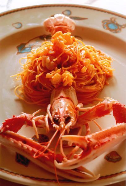 Scampi con pasta all'arancia, serviti su un piatto decorato.