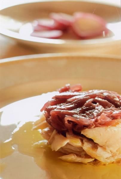 Primo piano di un piatto gourmet: pasta sfoglia a strati con una guarnizione di cipolle caramellate, servita con una salsa.