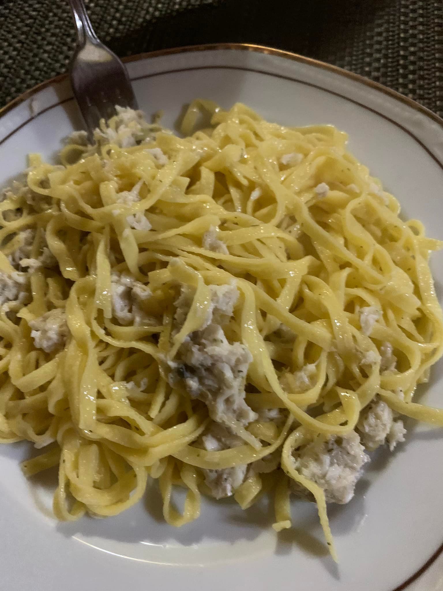 Piatto di fettuccine con salsa cremosa e pezzi di carne.