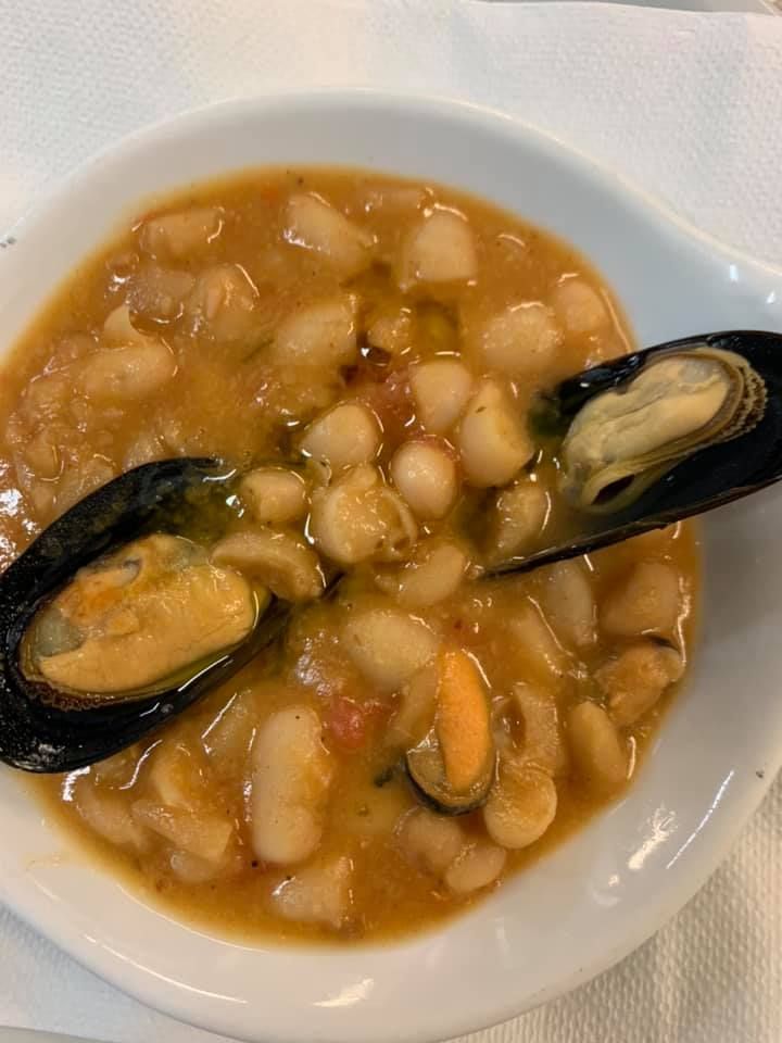 Stufato di fagioli bianchi con cozze in una ciotola bianca.