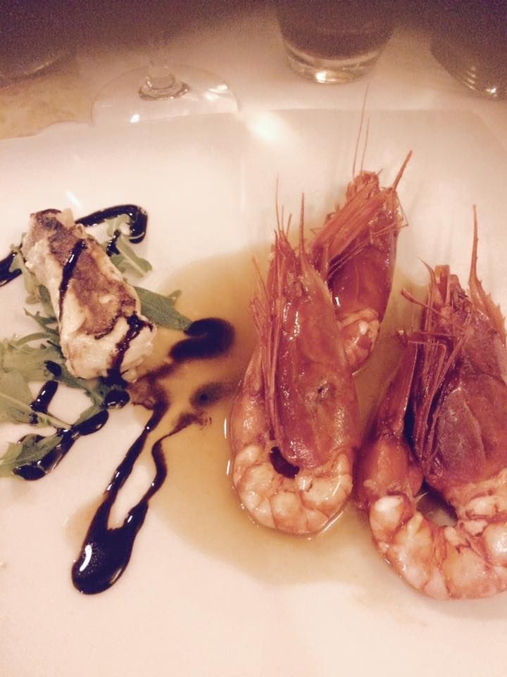 Piatto di frutti di mare: tre gamberi, un pezzo di pesce fritto con un filo di aceto balsamico e verdure.