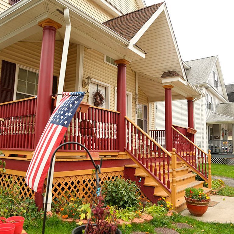A house with a porch and stairs has an american flag on the porch