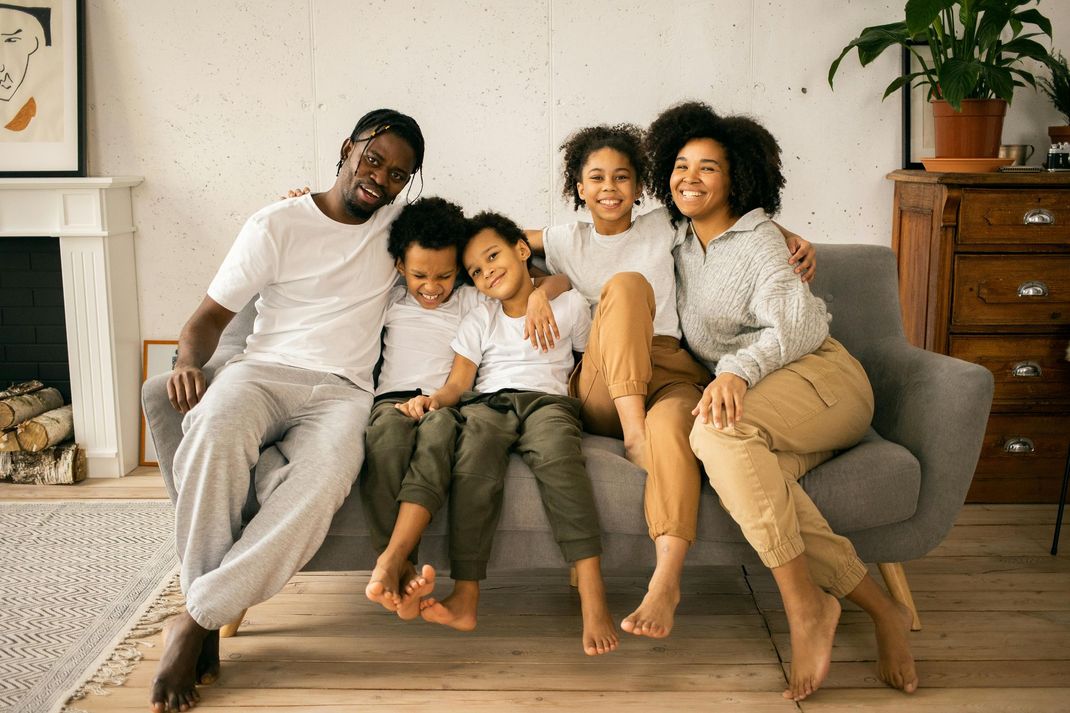 A family is sitting on a couch in a living room.