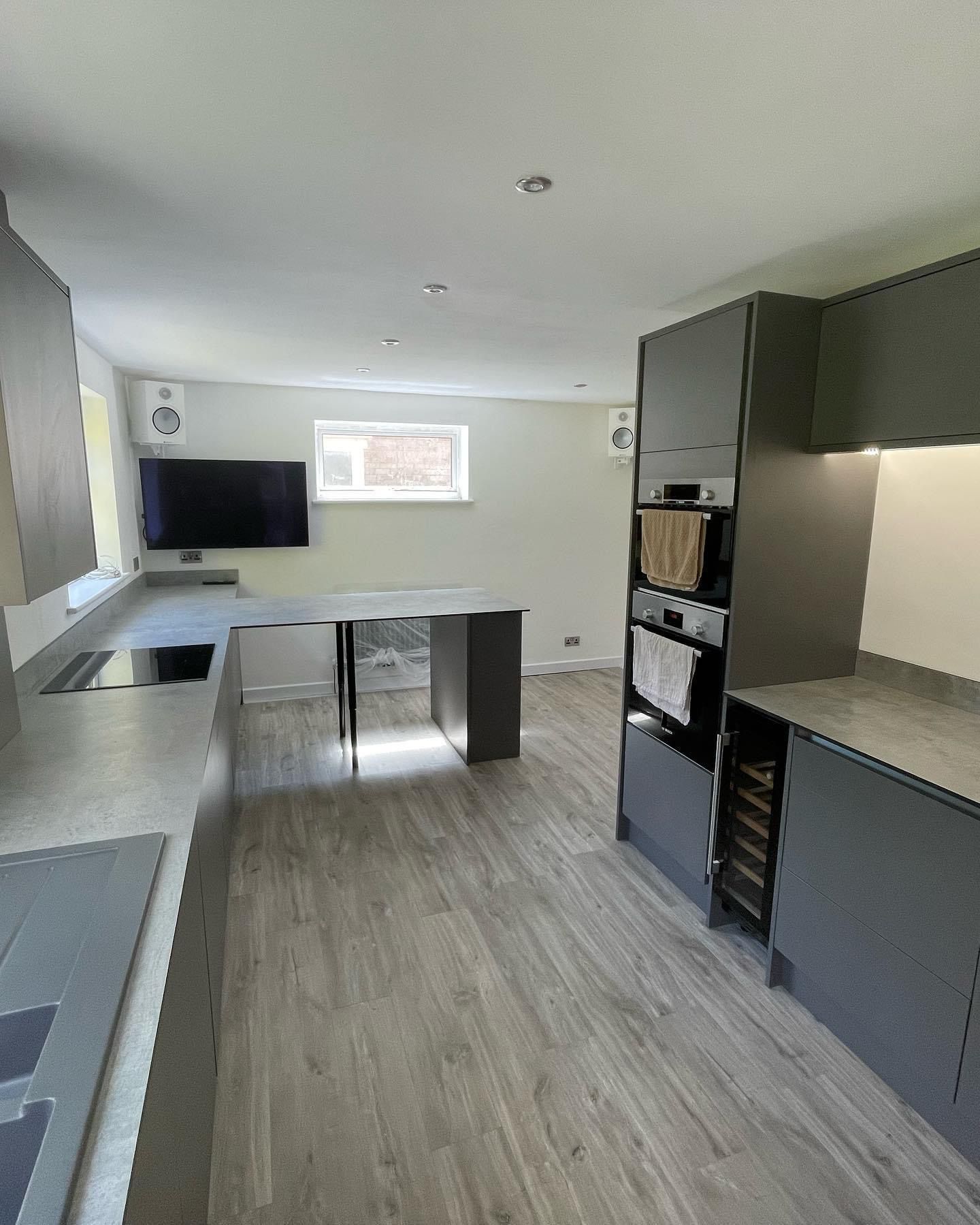a kitchen with gray cabinets and a flat screen tv .