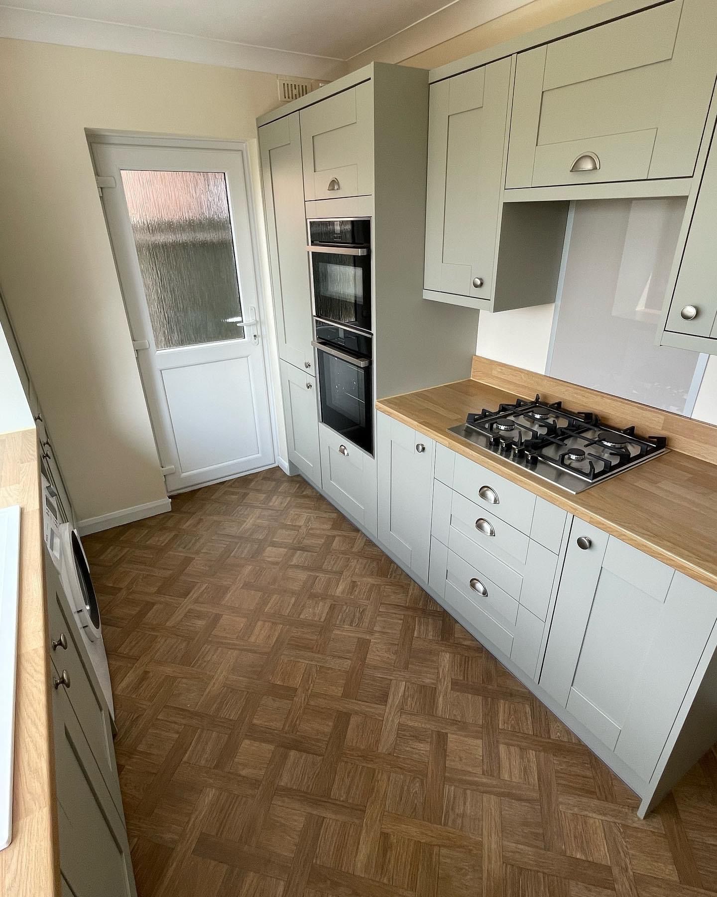 a kitchen with white cabinets and wooden counter tops and a stove top oven .